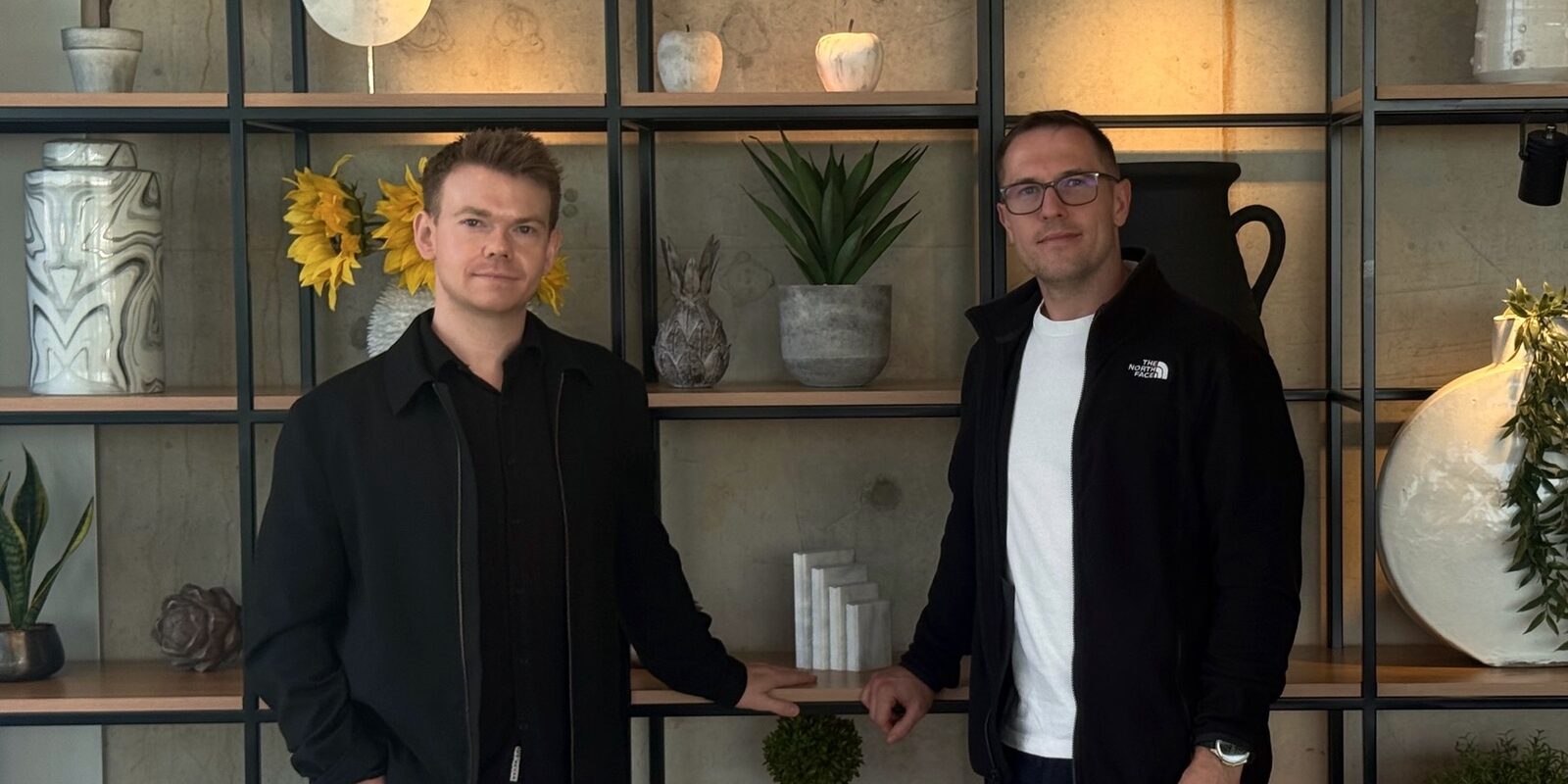 The IMMIX co-founders, Andrew Mann and David Twomey, standing in front of a shelving unit.
